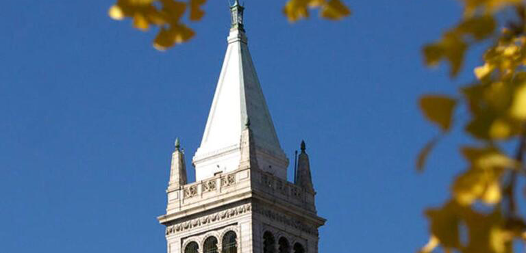 Top of Sather Tower with yellow ginkgo leaves framing the right side of photo