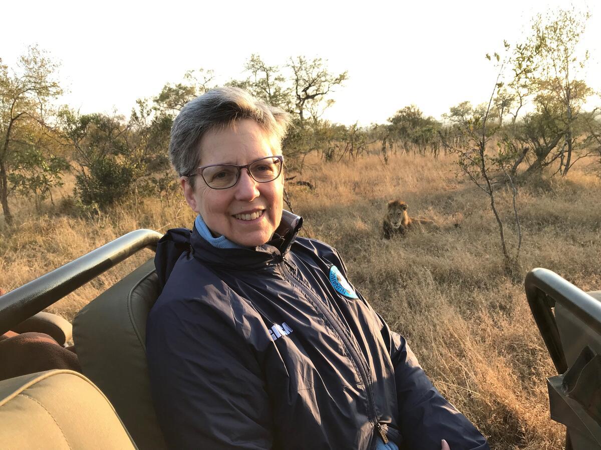 Deb Nolan posing in safari with lion in background